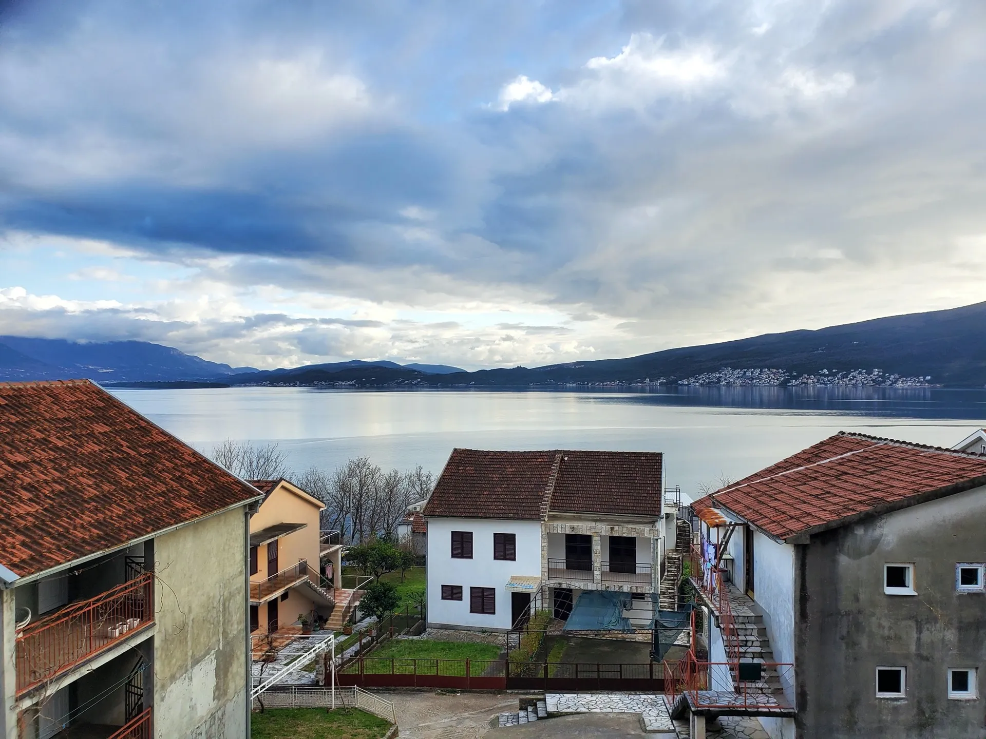 Blick auf das Meer und die Berge vom Hotel in Bijela, Montenegro: Privathäuser mit Ziegeldächern und ein panoramischer Meerblick.