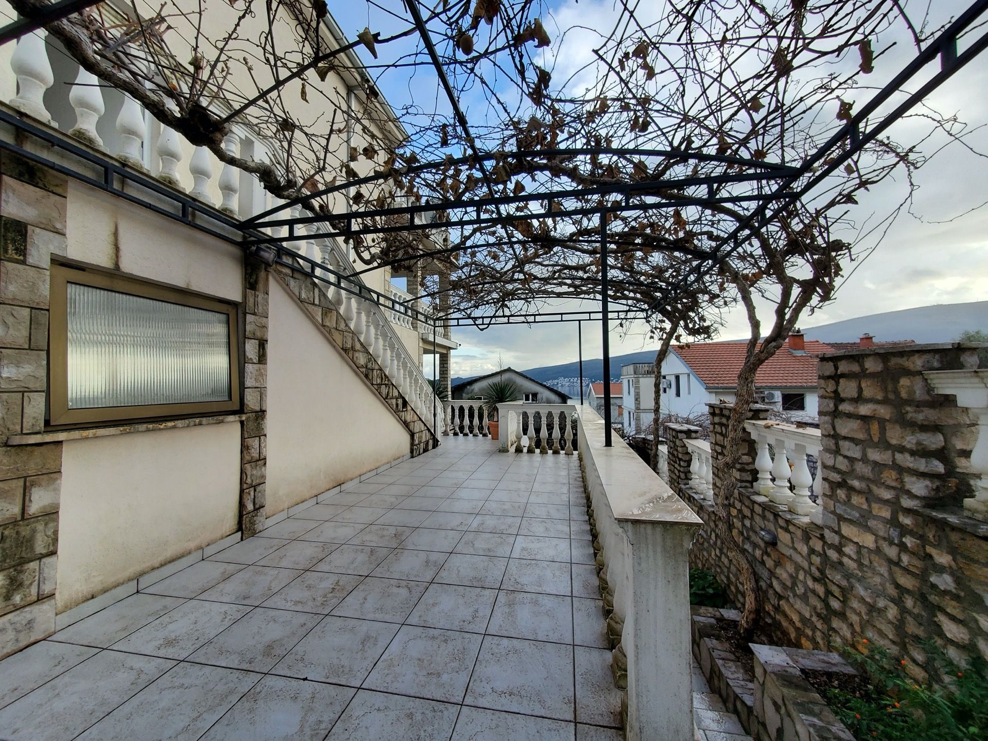 Taras hotelu w Bijeli, Czarnogóra: balkon z kamiennym wykończeniem, balustradą i zadaszeniem z winorośli.