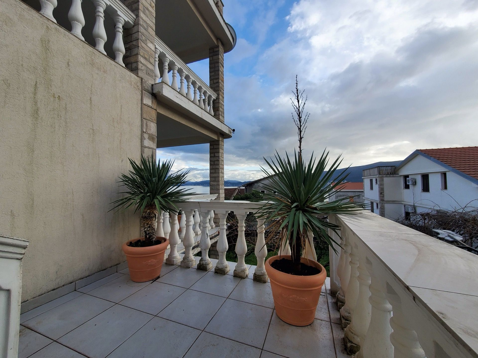 Balkon hotelu w Bieli, Czarnogóra: taras z balustradą, roślinami doniczkowymi i panoramicznym widokiem na morze.