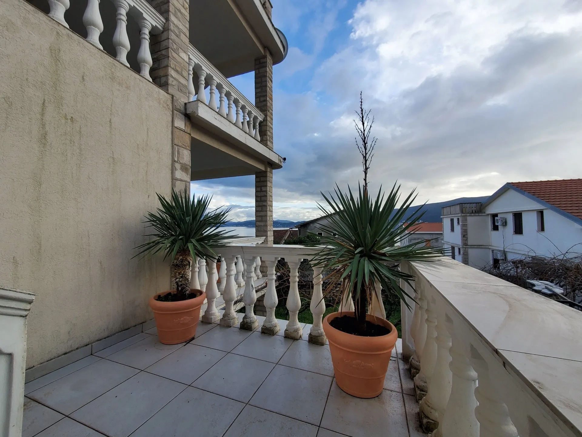 Hotelbalkon in Bijela, Montenegro: Terrasse mit Balustrade, Topfpflanzen und Panoramablick auf das Meer.