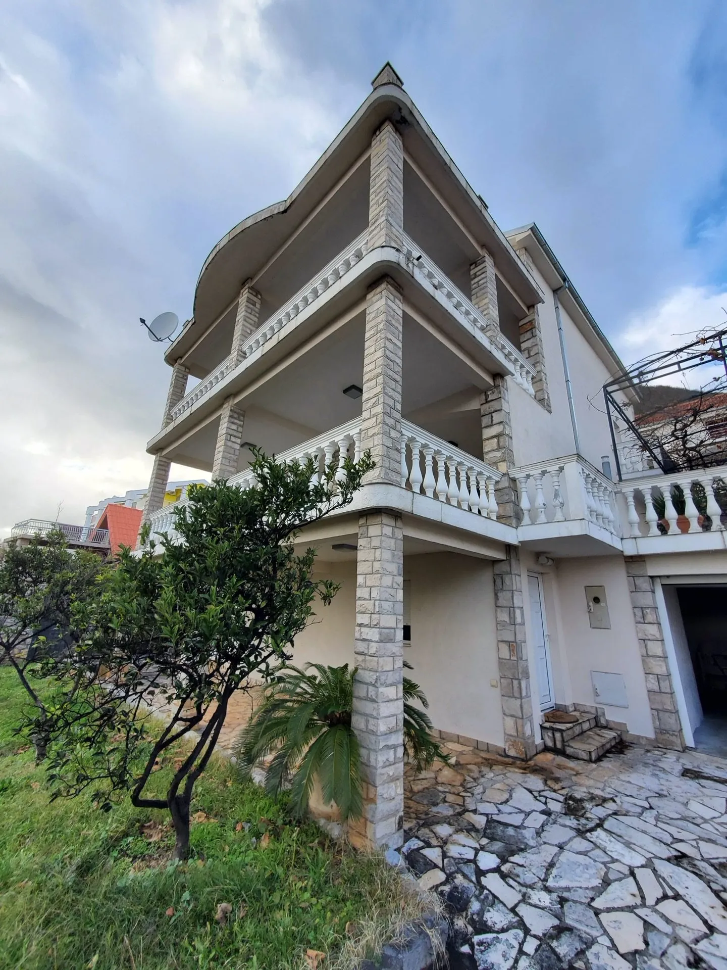Dreistöckiges Hotel in Bijela, Montenegro: Fassade mit Steinverkleidung, großzügigen Terrassen und Balustraden.