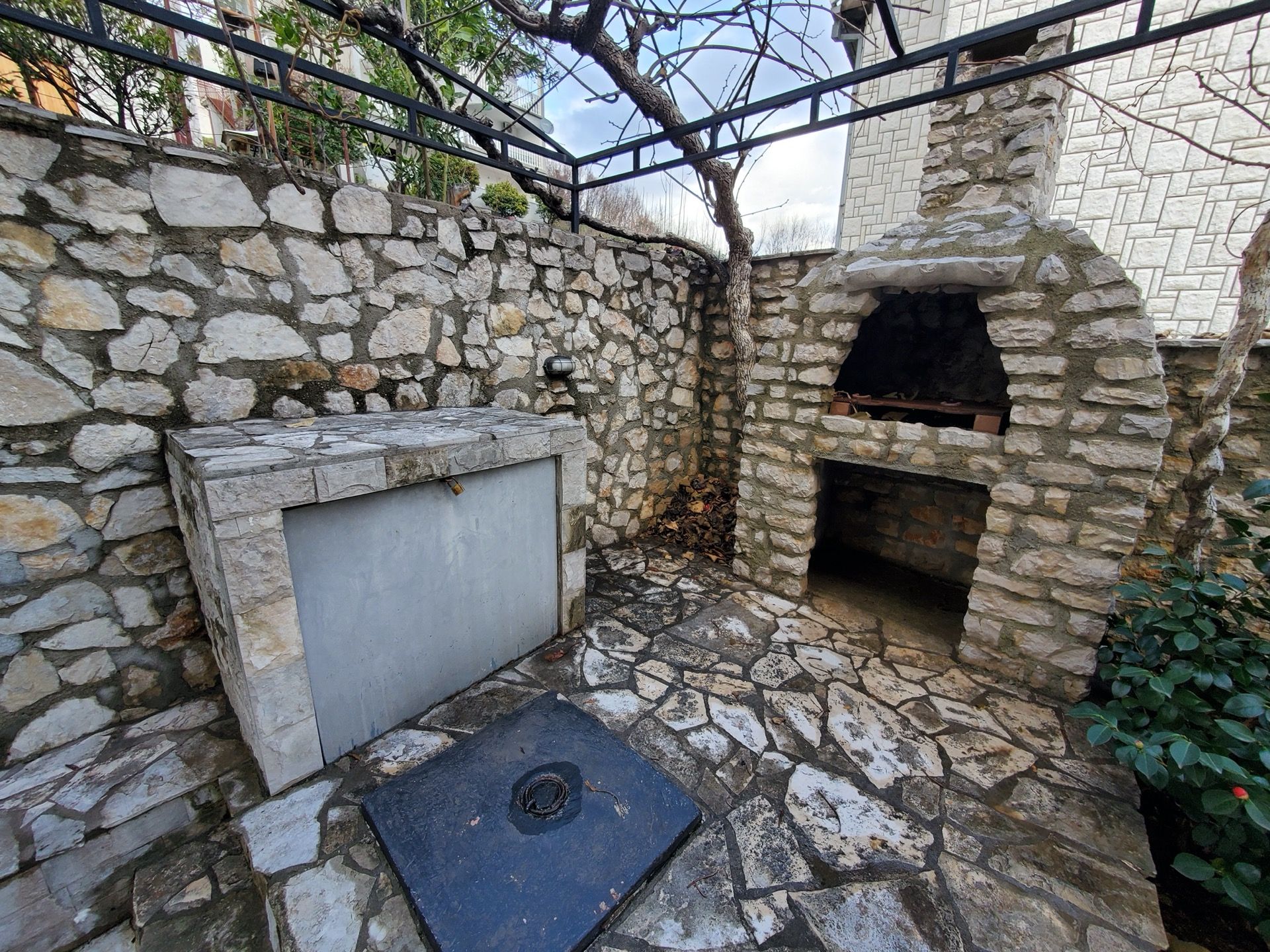Strefa barbecue z kamiennym grillem i tarasem w hotelu w mieście Bijela, Czarnogóra. Przytulny dziedziniec wykończony kamieniem.