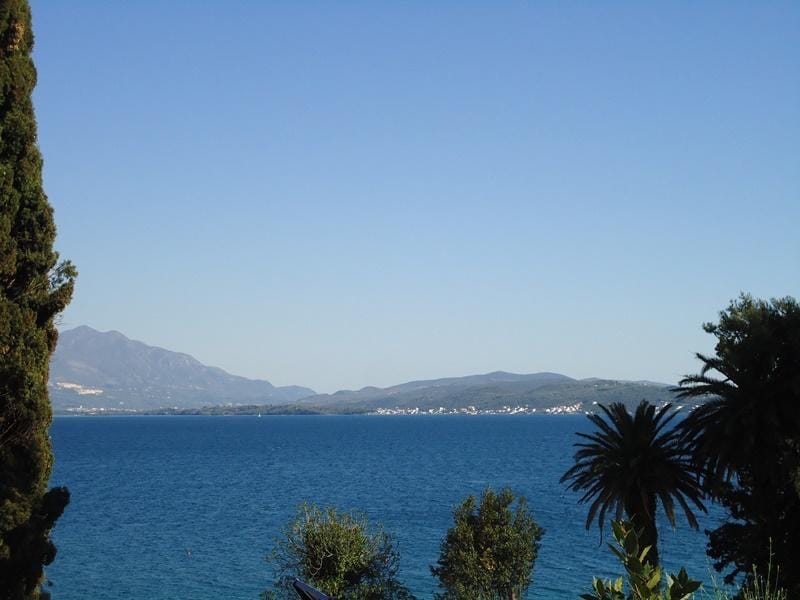 Karadağ, Bijela’daki arsa üzerinden deniz ve dağların panoramik manzarası, selvi ve palmiyelerle çevrili.