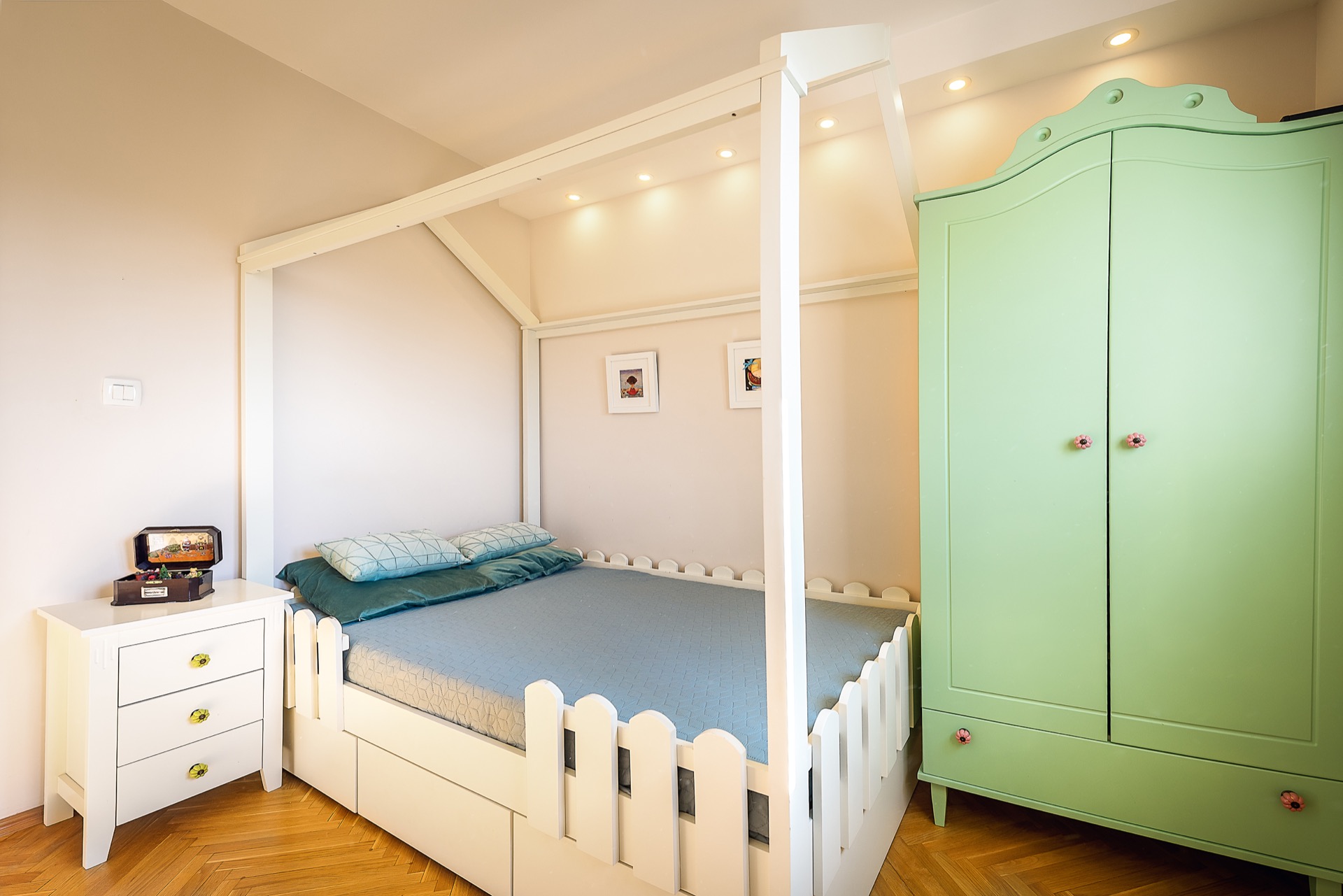 Kinderzimmer in einer Wohnung in Budva, Montenegro: weißes Hausbett, mintfarbener Kleiderschrank und Parkettboden.