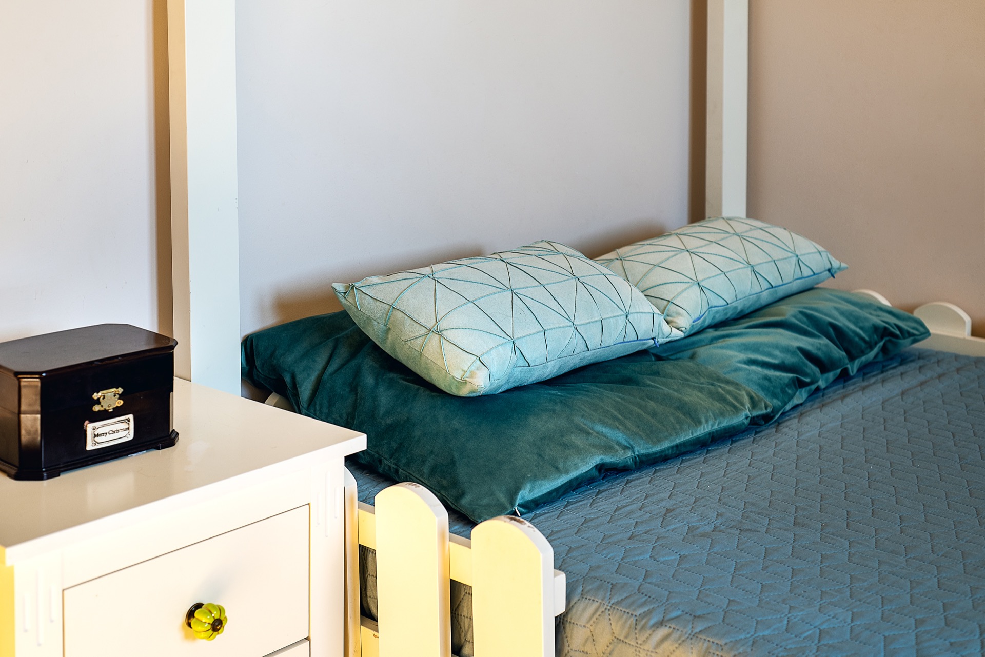 Gemütliches Schlafzimmer in einer Wohnung in Budva, Montenegro: weißes Bett mit smaragdgrüner Bettwäsche und Nachttisch im Interieur.