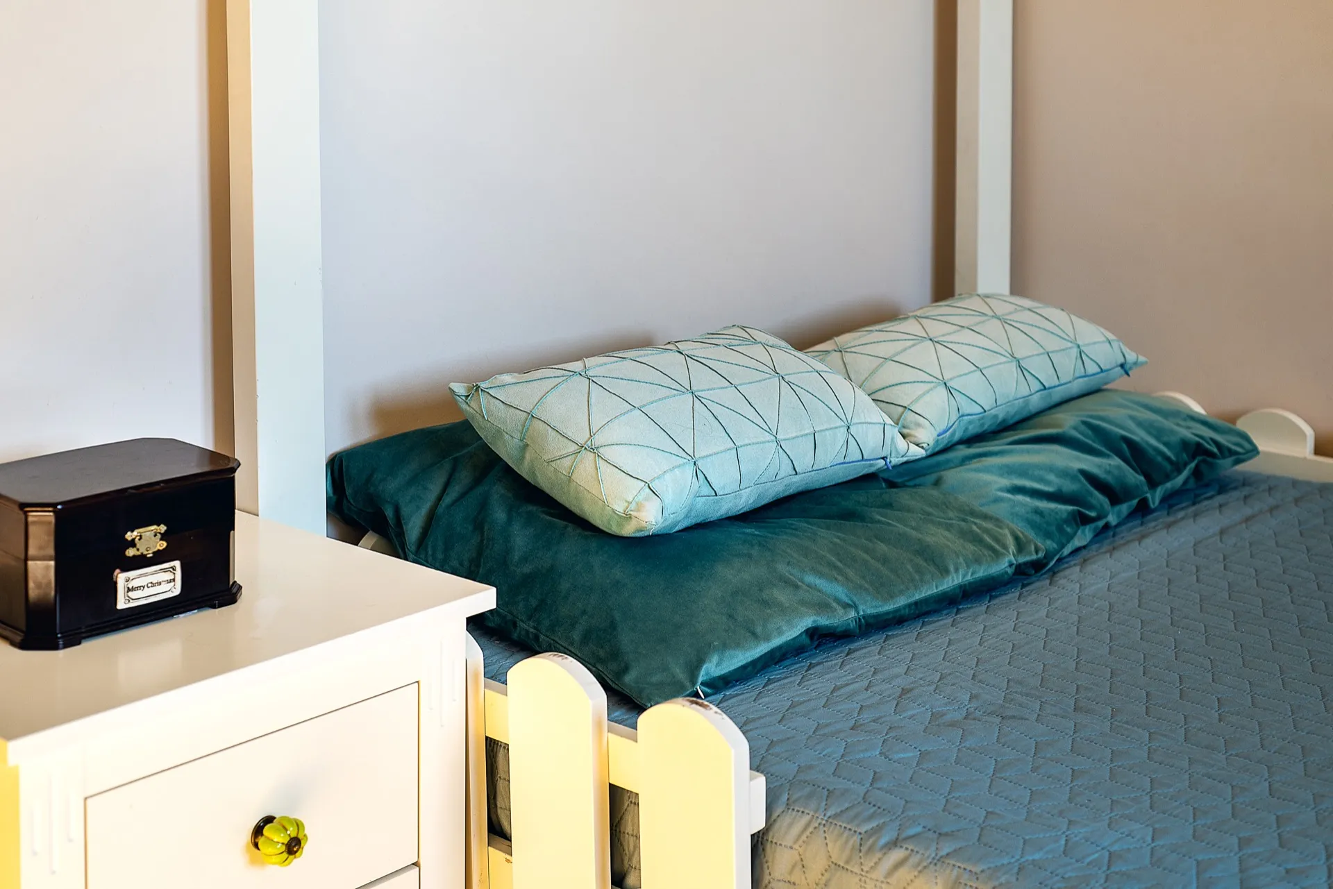 Cozy bedroom in an apartment in Budva, Montenegro: a white bed with emerald textiles and a bedside table in the interior.