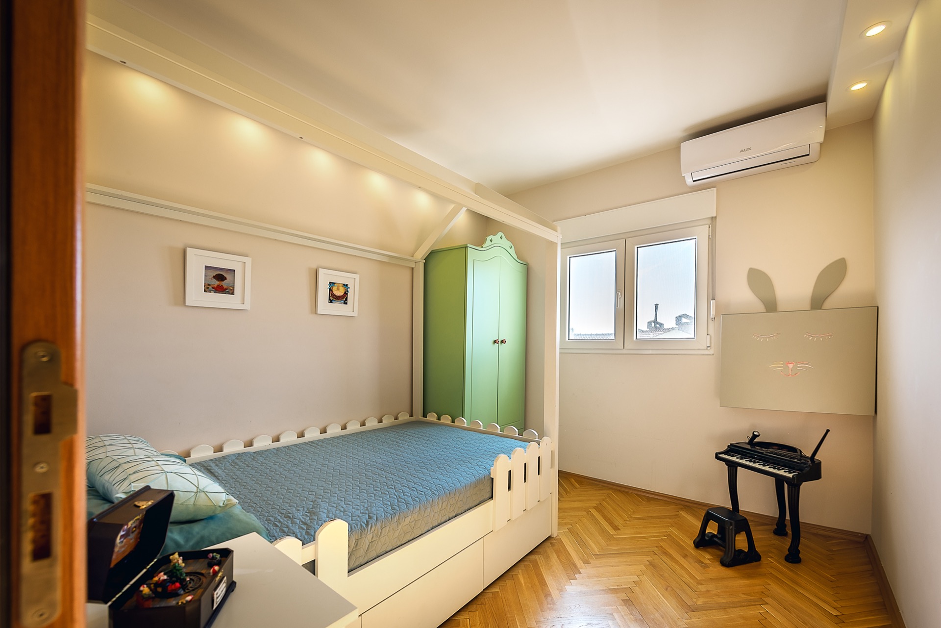 Kinderzimmer in einer Wohnung in Budva, Montenegro: Hausbett, grüner Schrank, Parkett und Klimaanlage im Interieur.
