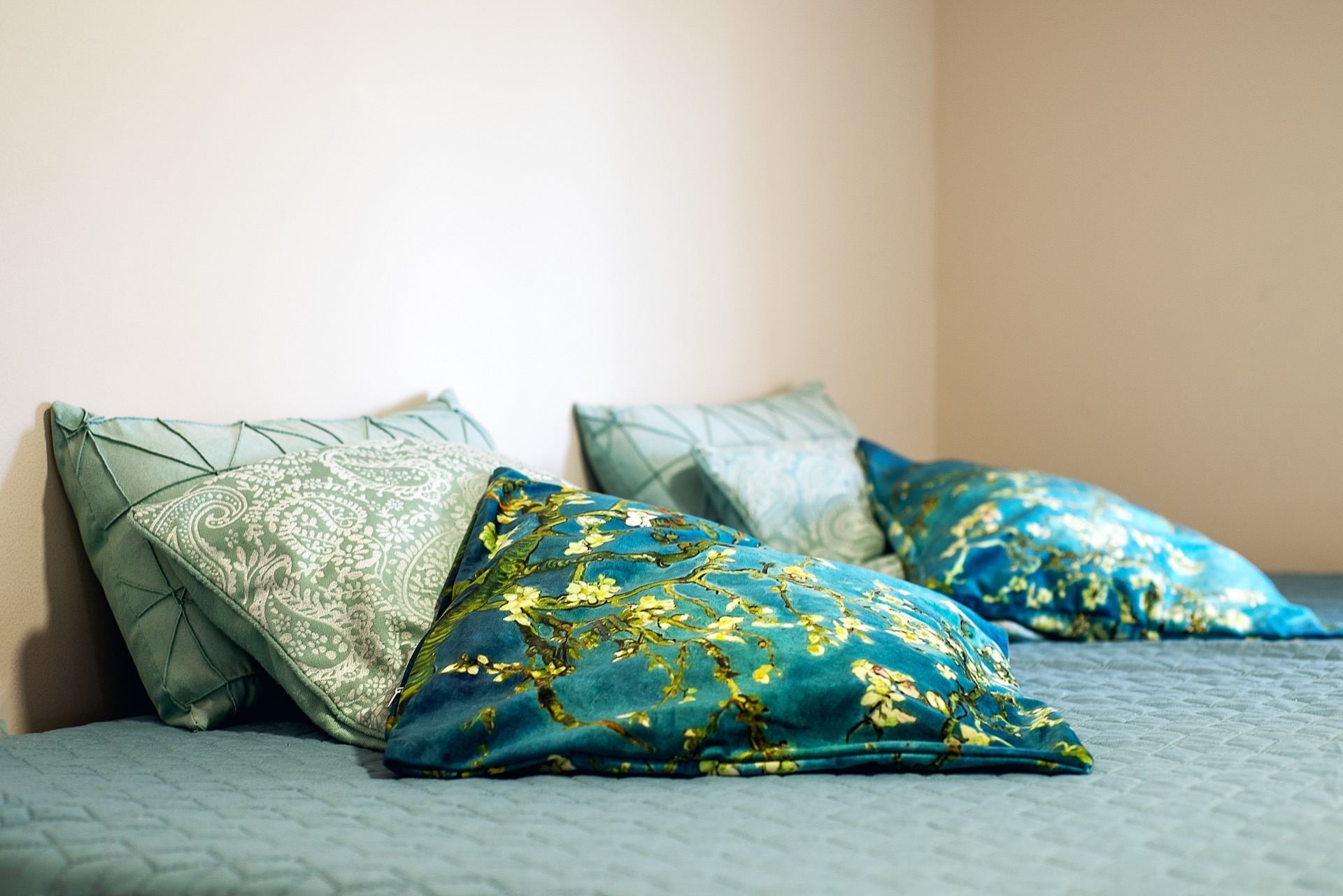 Gemütliches Schlafzimmer in einer Wohnung in Budva, Montenegro: Bett mit dekorativen Kissen in Türkistönen und helle Wände.