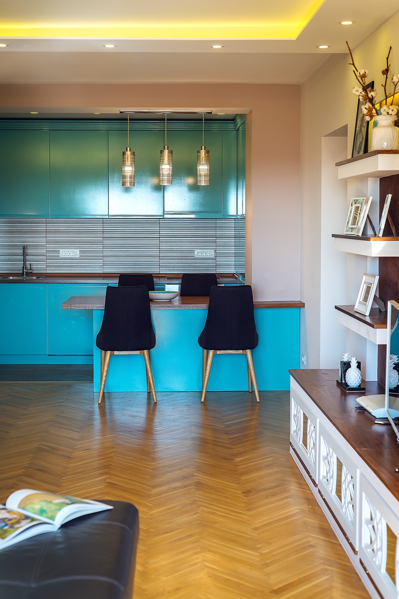 Moderne Küche mit türkisfarbener Einbauküche und Parkett in einer Wohnung in Budva, Montenegro: Essbereich und stilvolle Dekoration.