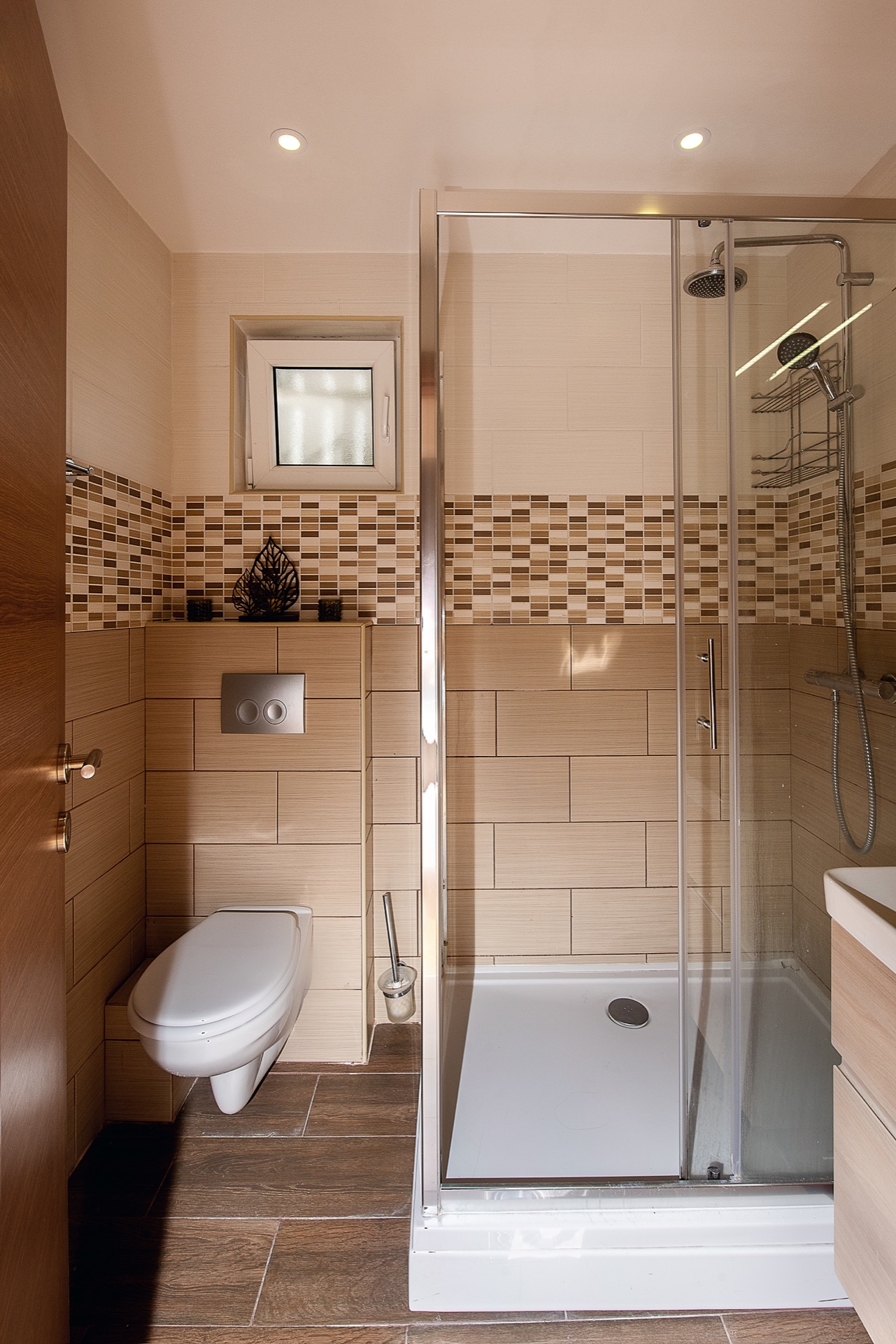 Modernes Badezimmer in einer Wohnung in Budva, Montenegro: Duschkabine, Hänge-WC und beige Fliesen.