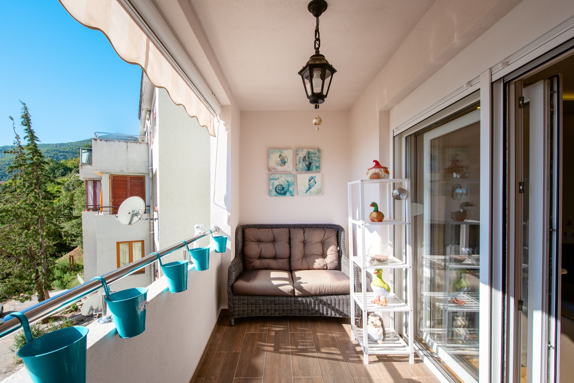 Gemütlicher Balkon mit Rattanmöbeln und Bergblick in einer Wohnung, Budva, Montenegro.