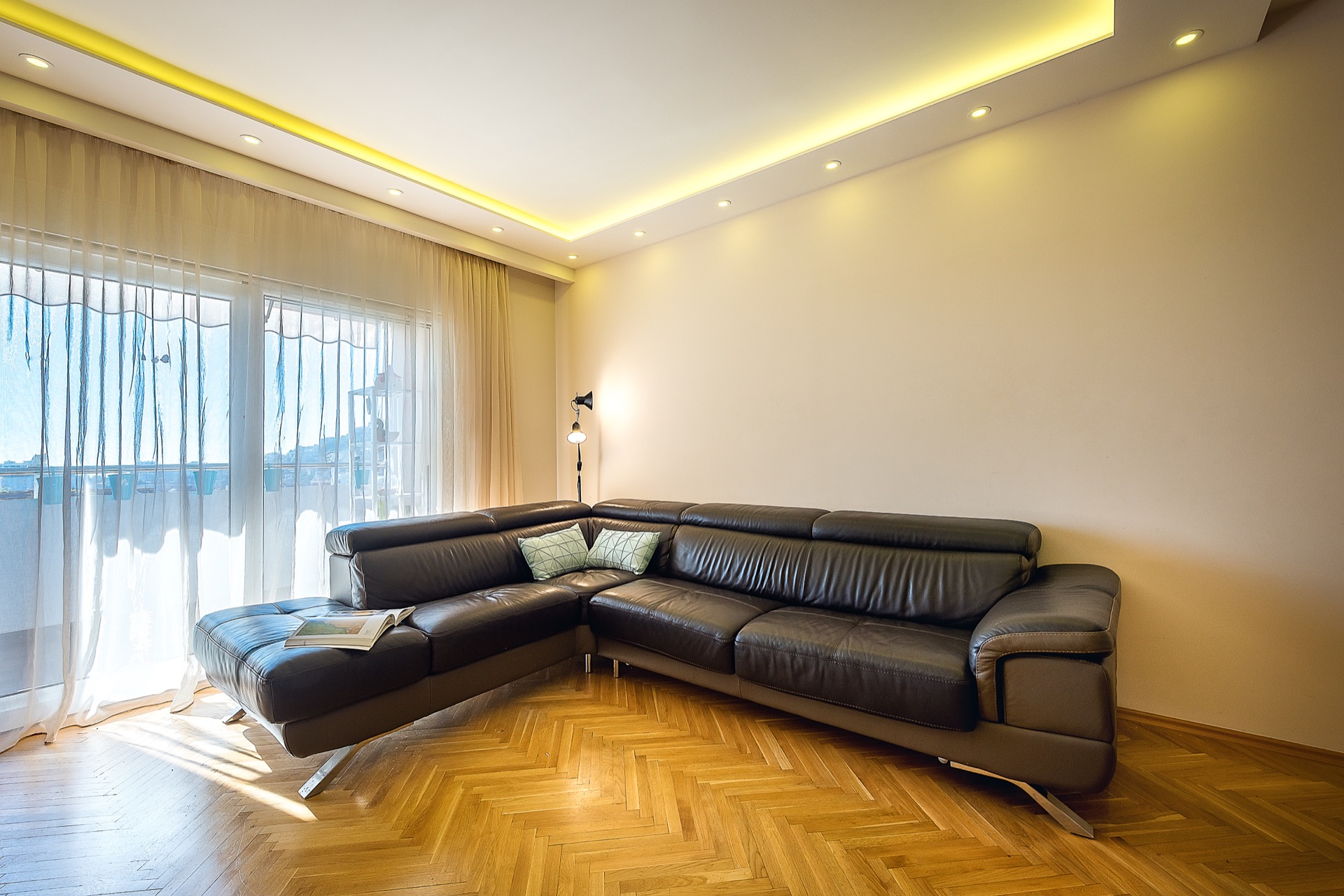 Modernes Wohnzimmer mit Lederecksofa und Parkett in einer Wohnung in Budva, Montenegro, mit Zugang zum Balkon.