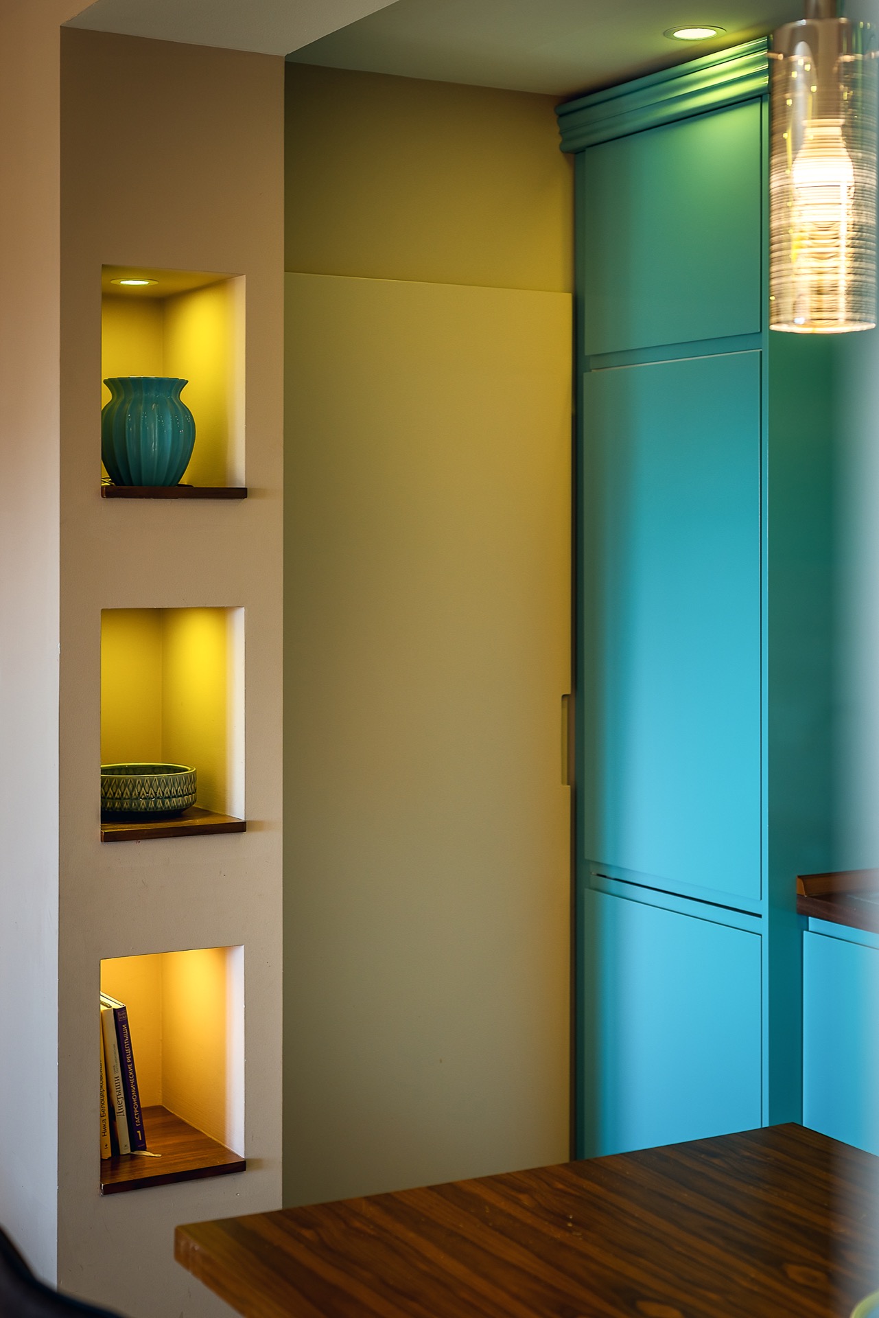 Moderne Küche in einer Wohnung in Budva, Montenegro: türkisfarbene Fronten, integrierte Nischen mit Beleuchtung und Dekor.