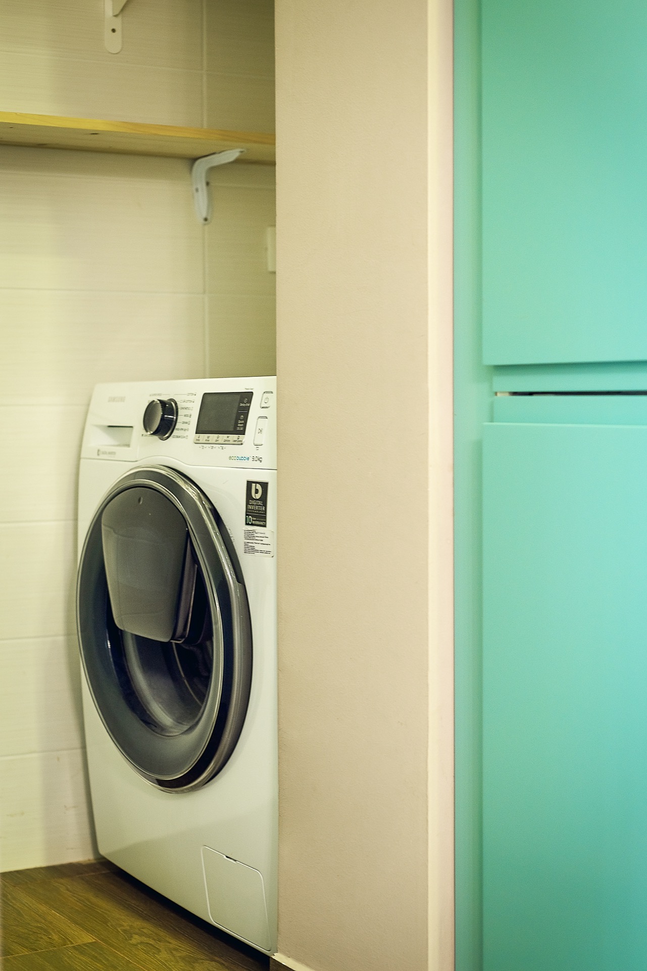 Samsung-Waschmaschine in einer Nische mit Regal in einer Wohnung in Budva, Montenegro: moderne Haushaltsgeräte und Innenraum.