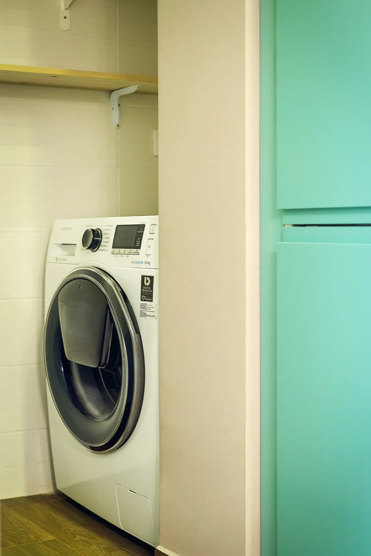 Samsung washing machine in a niche with a shelf in an apartment in Budva, Montenegro: modern appliances and interior.