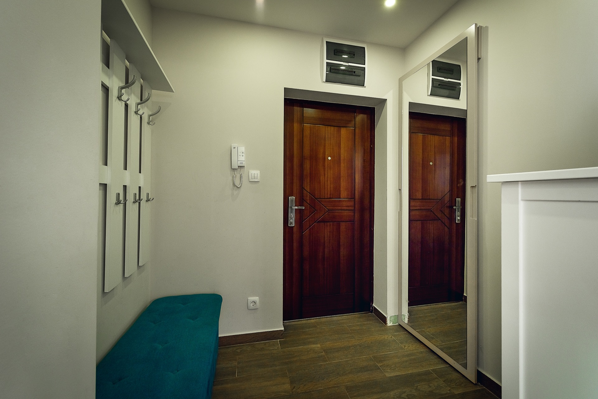 Moderne Diele mit Spiegel, Garderobe und blauer Bank in einer Wohnung in Budva, Montenegro.