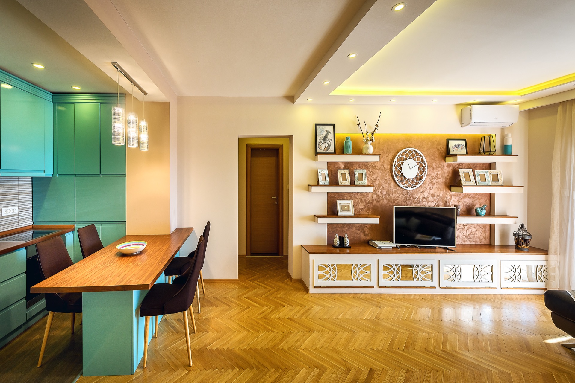 Modernes Wohnzimmer mit türkisfarbener Küche und Essbereich in einer Wohnung in Budva, Montenegro. Parkett und Designermöbel.
