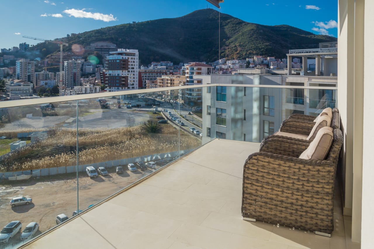 Balkon mit Rattanmöbeln und Panoramablick auf die Stadt und die Berge in einer Wohnung, Budva, Montenegro.