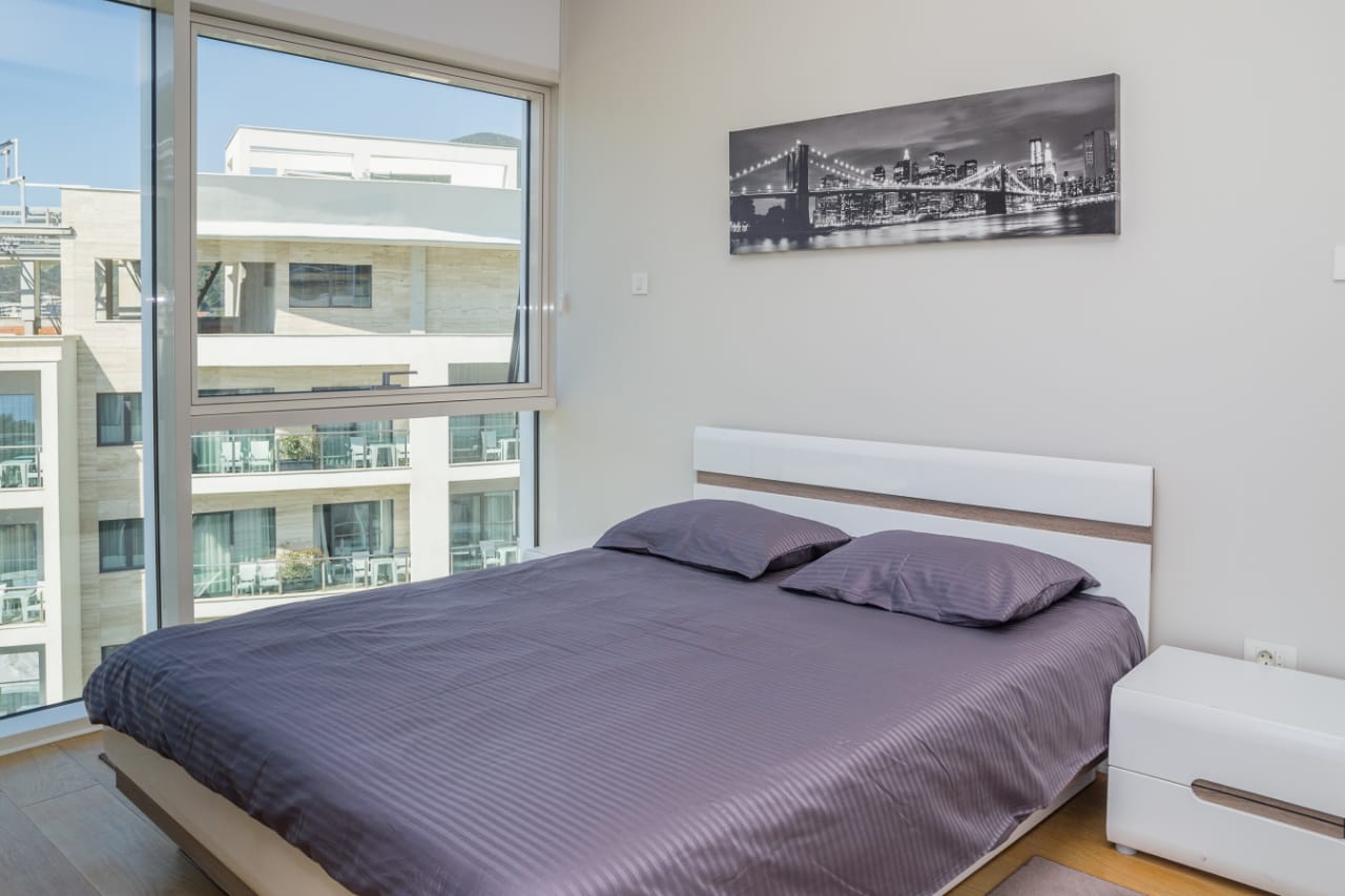 Modernes Schlafzimmer mit Doppelbett und Panoramafenster in einer Wohnung in Budva, Montenegro.