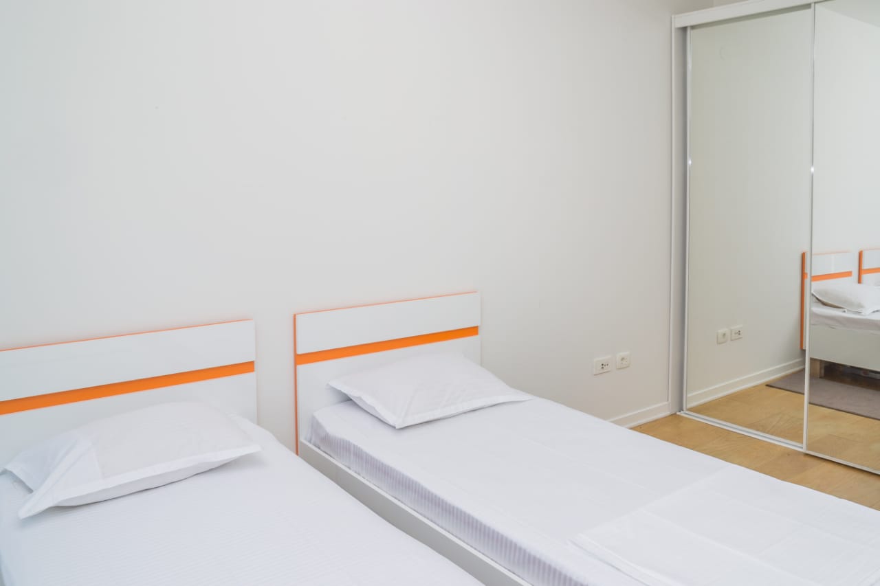 Helles Schlafzimmer mit zwei Einzelbetten und einem Spiegelschiebetürenschrank in einer Wohnung, Stadt Budva, Montenegro.