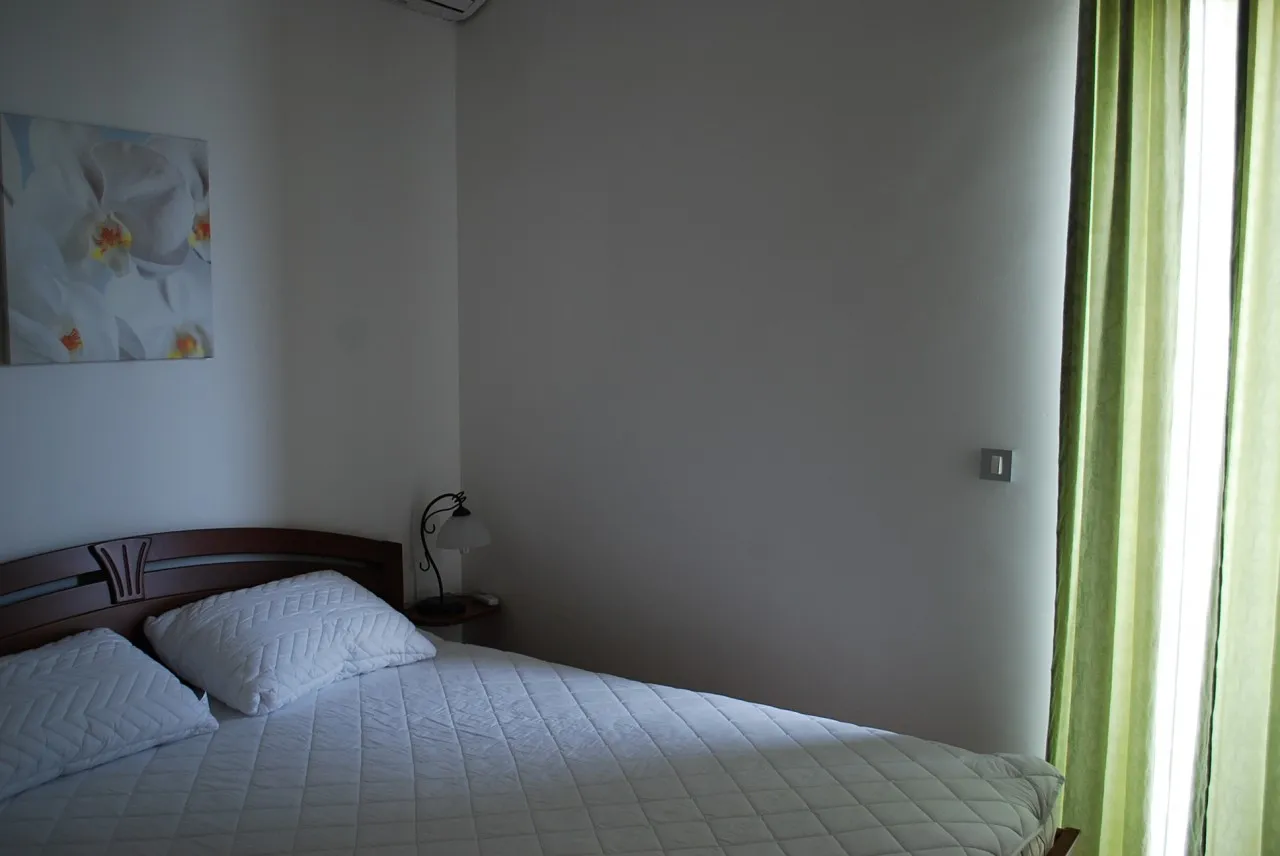 Bedroom featuring a double bed with white bedding, a bedside lamp, and a floral orchid painting on the wall.