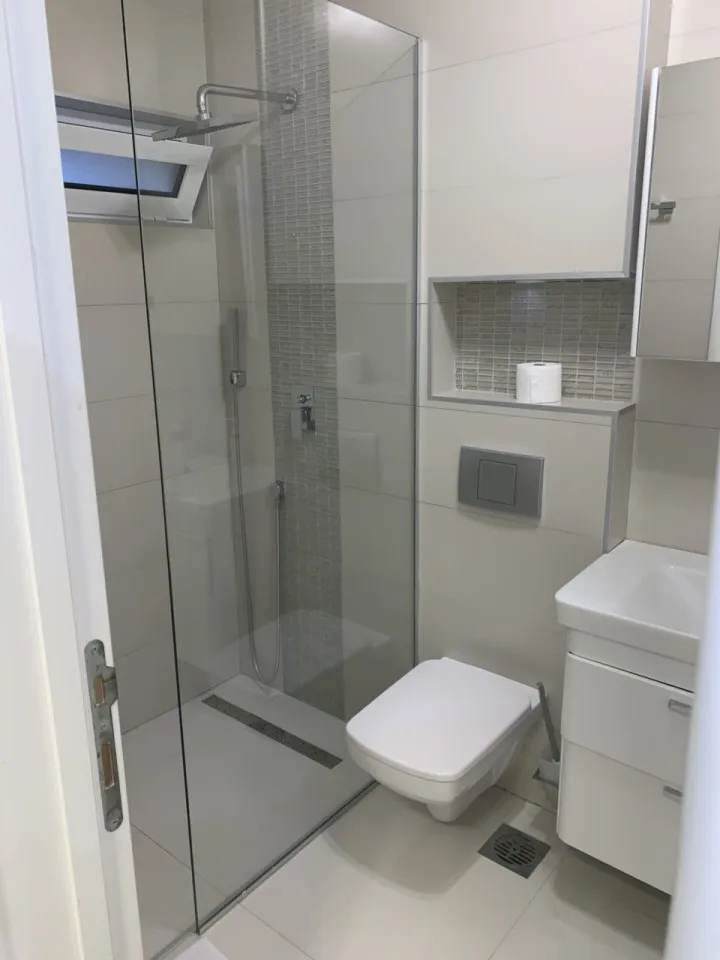 Ein modernes Badezimmer mit Dusche, Toilette, Waschbecken und Schränken.