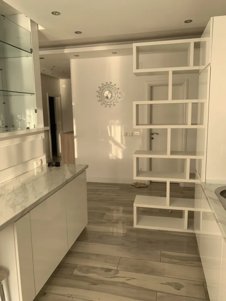 Ein modernes Kücheninterieur mit Theke, Schränken und dekorativen Regalen.