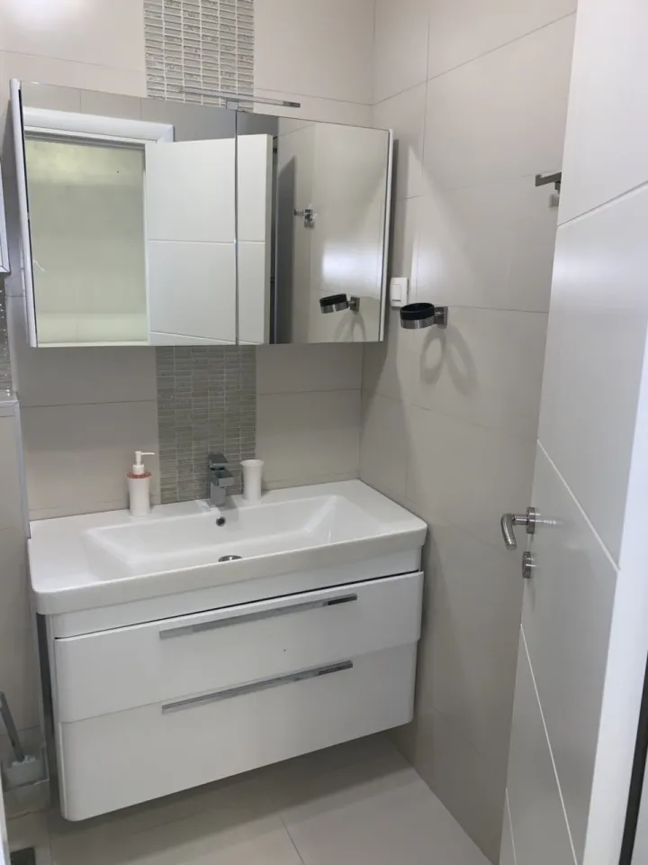 Ein modernes Badezimmer mit einem weißen Waschbecken und Spiegelschrank.