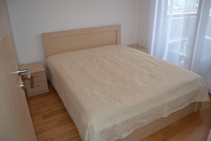 Bright bedroom with a double bed and parquet flooring in an apartment in Bečići, Montenegro, with access to the balcony.