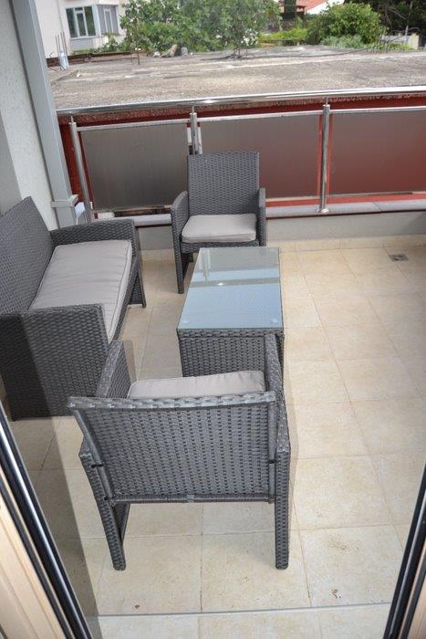 Cozy terrace with wicker furniture in an apartment in Bečići, Montenegro: view of the balcony with a sofa and table.