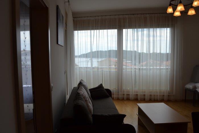 Living room in an apartment in Bečići, Montenegro: panoramic window with sea view, a soft sofa, and a coffee table.