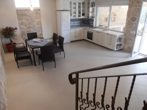 Küche mit Essbereich, Steinverkleidung und Möbeln in einer Villa, Luštica, Montenegro. Geräumiger Innenraum mit Zugang zur Terrasse.