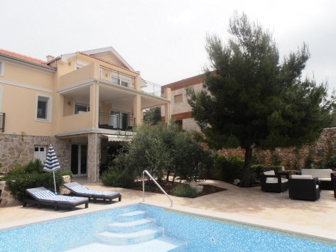 Zweistöckige Villa mit Pool, Terrasse und Ruhebereich in Luštica, Montenegro: Blick auf die Fassade und den gepflegten Hof.