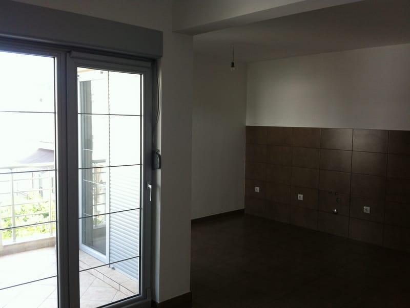 Kücheninterieur in einer Wohnung in Petrovac, Montenegro: dunkle Fliesen, Zugang zum Balkon mit Panoramaverglasung.