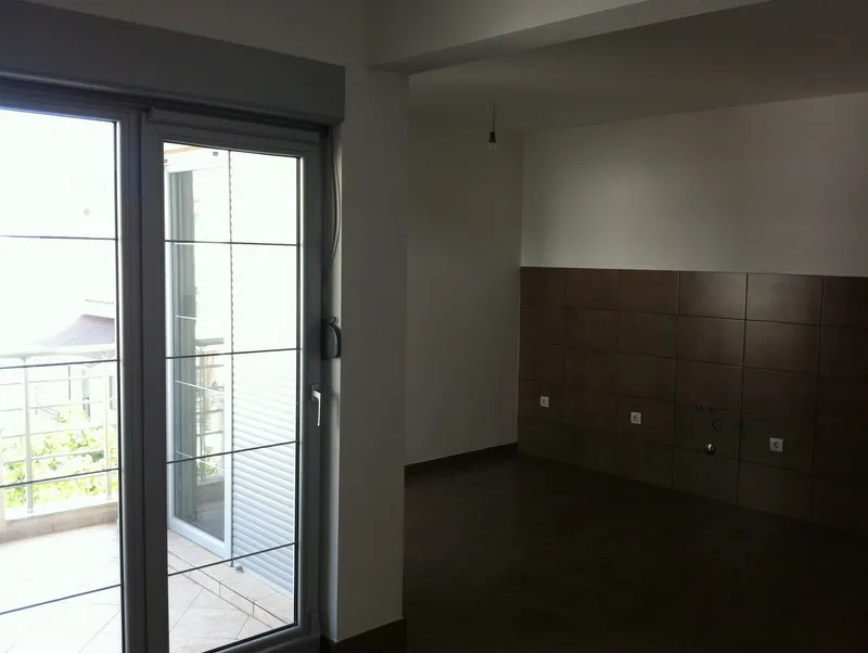 Ein Zimmer mit Balkontür und dunklen Wandfliesen, wahrscheinlich eine Küche.