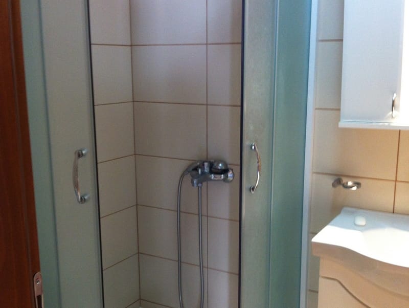 Badezimmer mit Duschkabine und hellen Fliesen in einer zum Verkauf stehenden Wohnung in Petrovac, Montenegro.