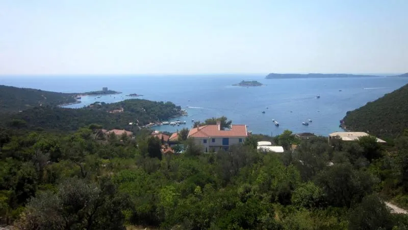 Panoramski pogled na more i zaliv Žanjica, Crna Gora, sa zemljišne parcele okružene zelenilom i mediteranskim planinama.