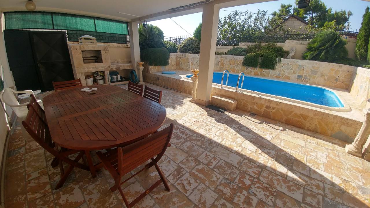 Un patio extérieur avec une table à manger, une cheminée et une piscine.