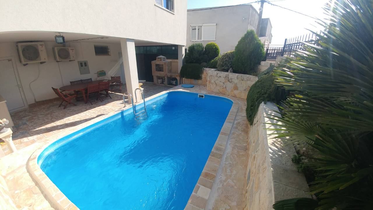 Grande piscine extérieure avec terrasse et coin salon.