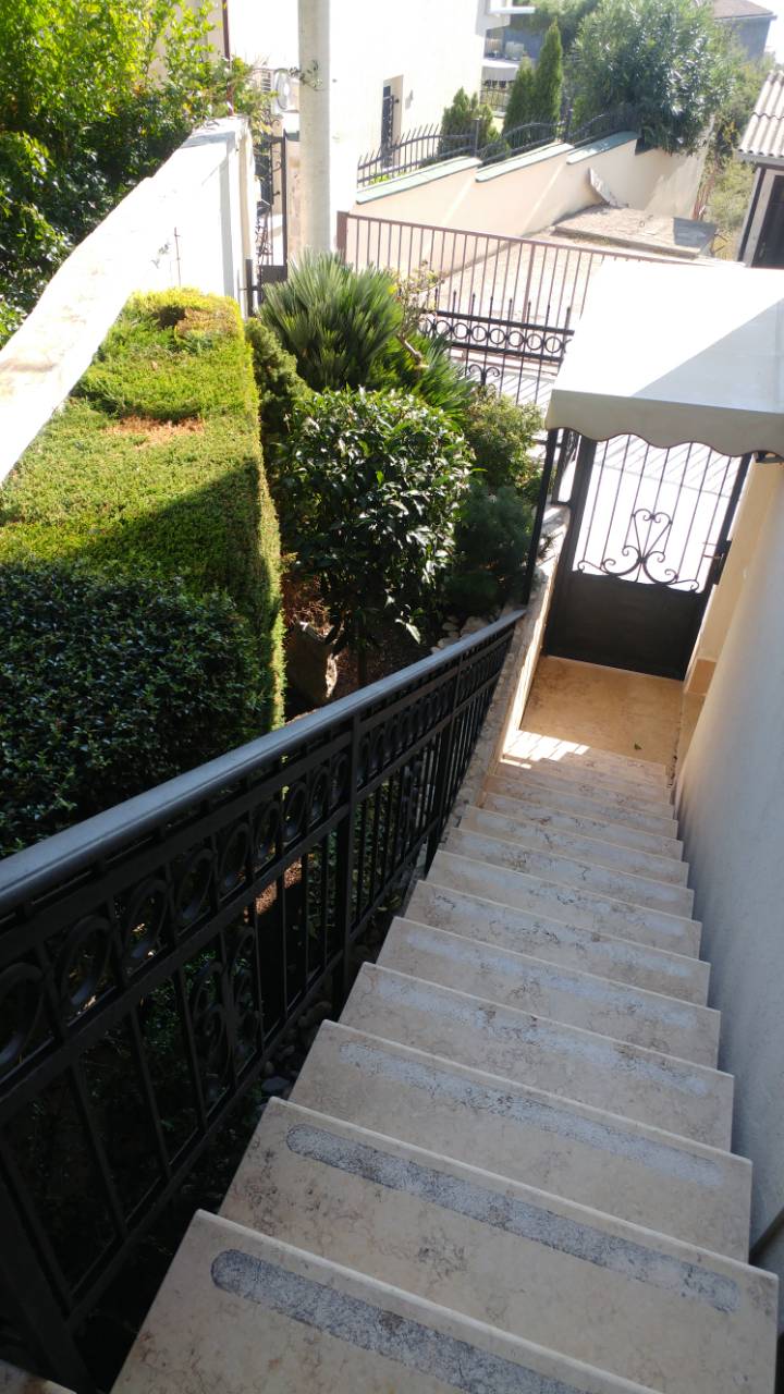 Vue plongeante sur un escalier extérieur avec des rampes et de la verdure.