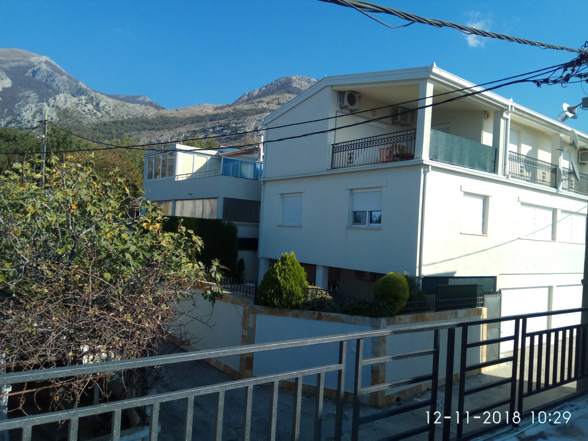 Vue d'une maison blanche à deux étages avec des montagnes en arrière-plan