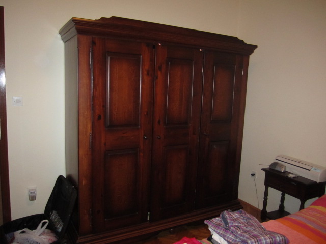 Massiver Holzschrank im Schlafzimmer eines Hauses in Tivat, Montenegro. Daneben ein Nachttisch und eine Klimaanlage.