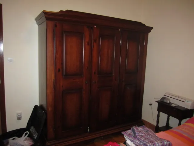 Massiver Holzschrank im Schlafzimmer eines Hauses in Tivat, Montenegro. Daneben ein Nachttisch und eine Klimaanlage.
