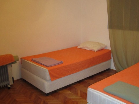 Schlafzimmer mit zwei Einzelbetten in einem Haus in Tivat, Montenegro: Parkettboden, helle Wände und ein Ölradiator.