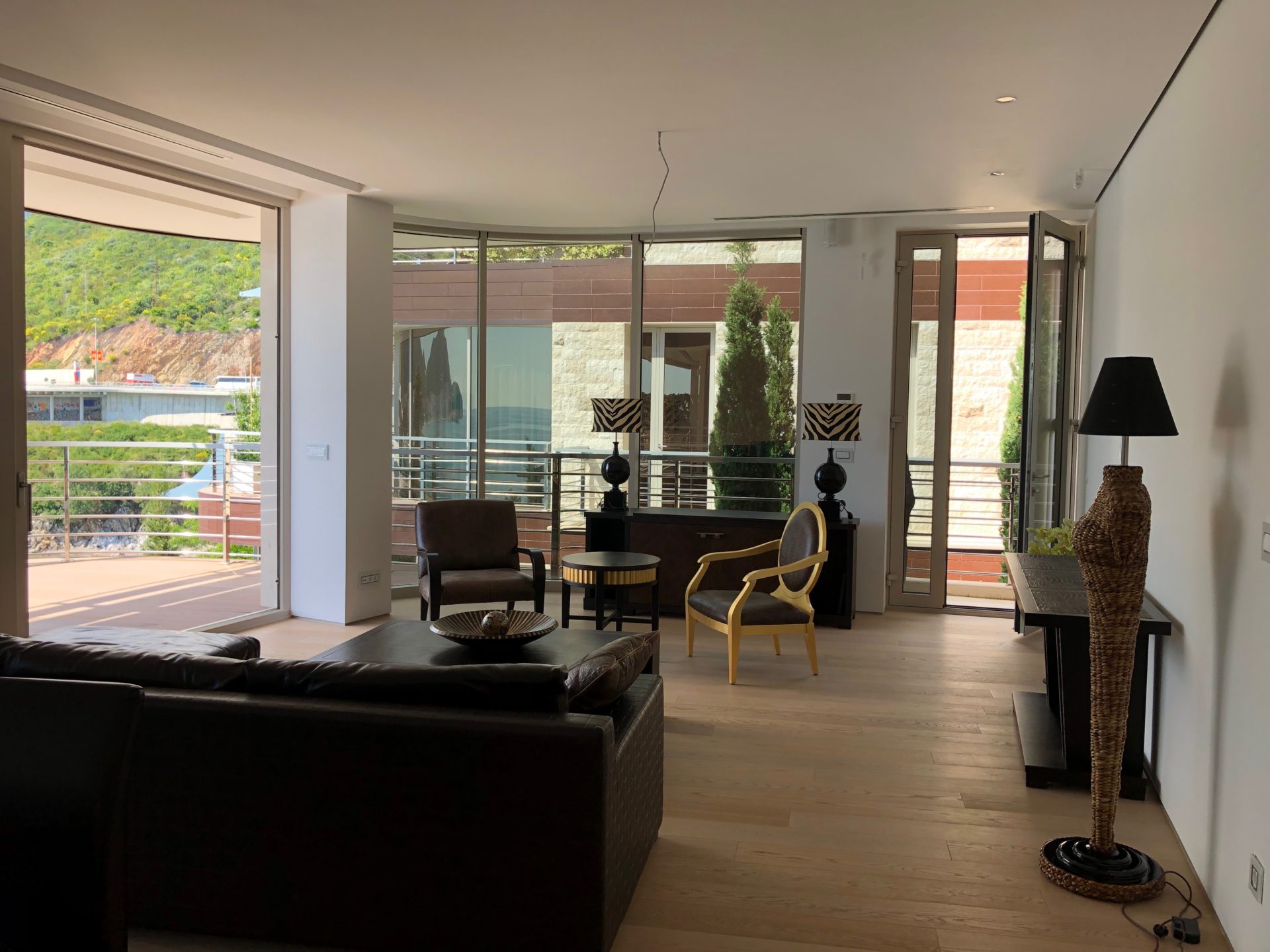 Geräumiges Wohnzimmer mit Panoramafenstern und Terrasse in einer exklusiven Wohnung, Budva, Montenegro. Modernes Interieur.