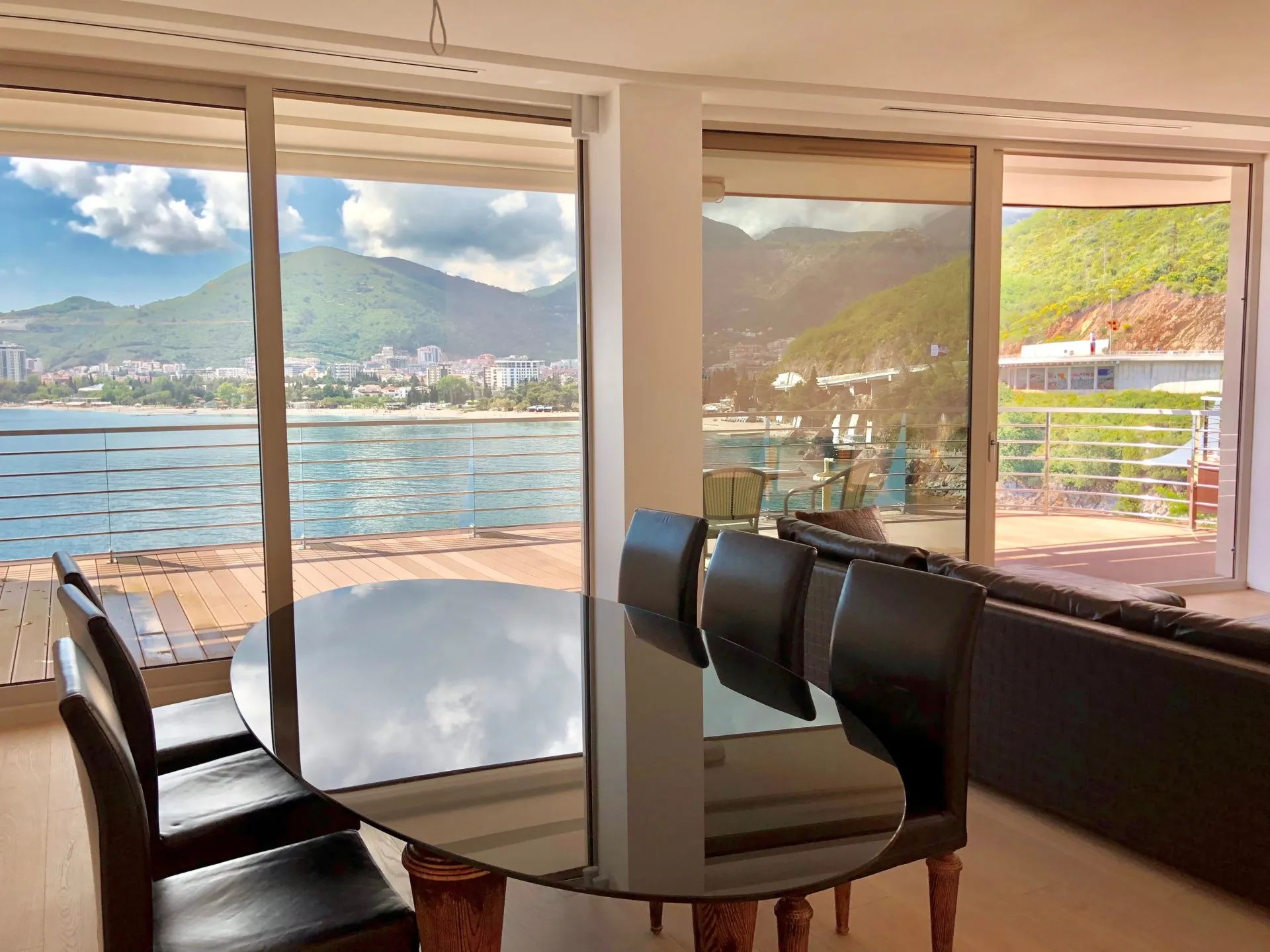 Wohnzimmer mit Panoramablick auf das Meer und die Berge in einer Wohnung in Budva, Montenegro: Esstisch und Terrasse.