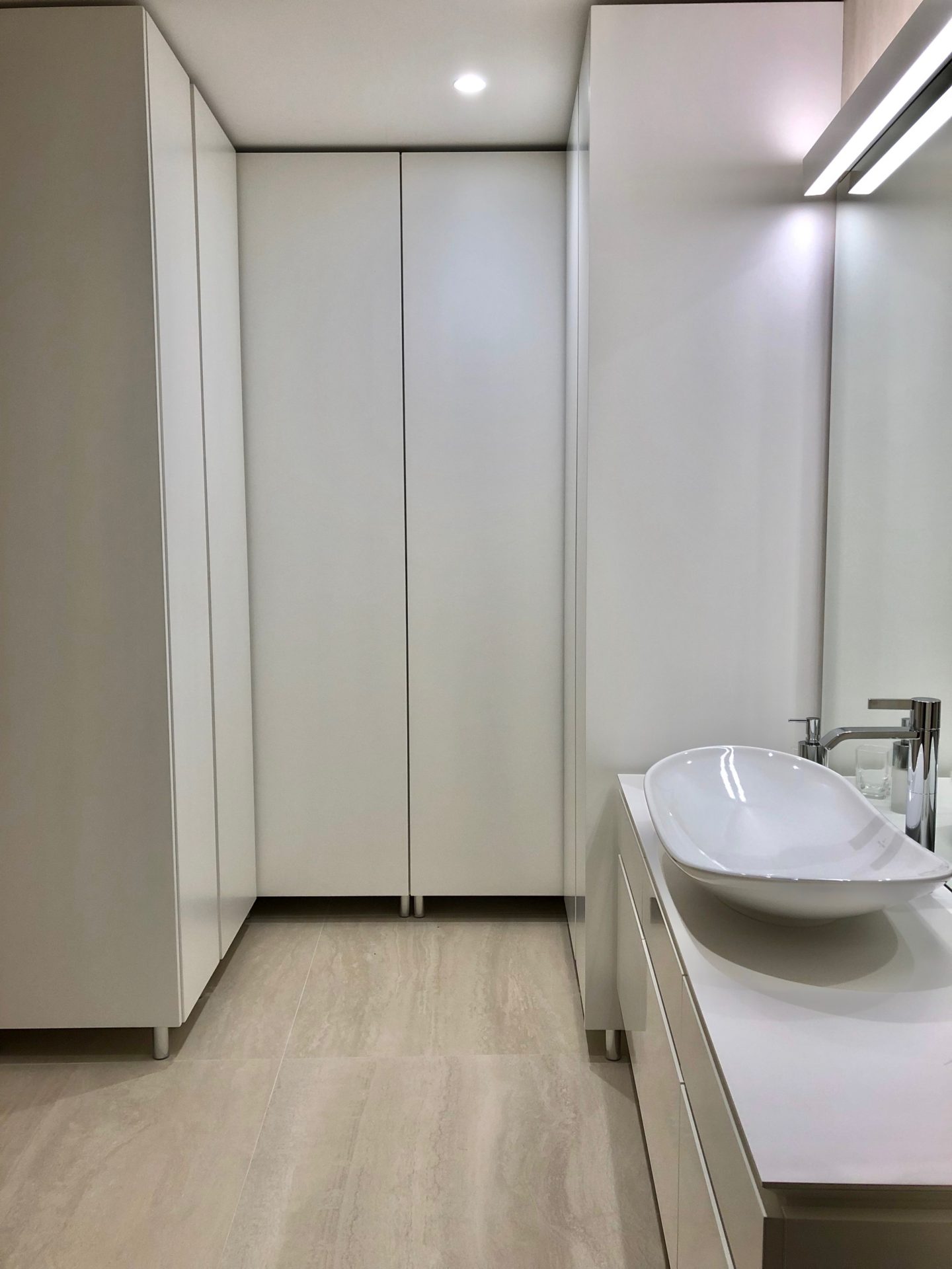 Modernes Badezimmer in einer Wohnung in Budva, Montenegro: weiße Möbel, Aufsatzwaschbecken und Einbauschränke.