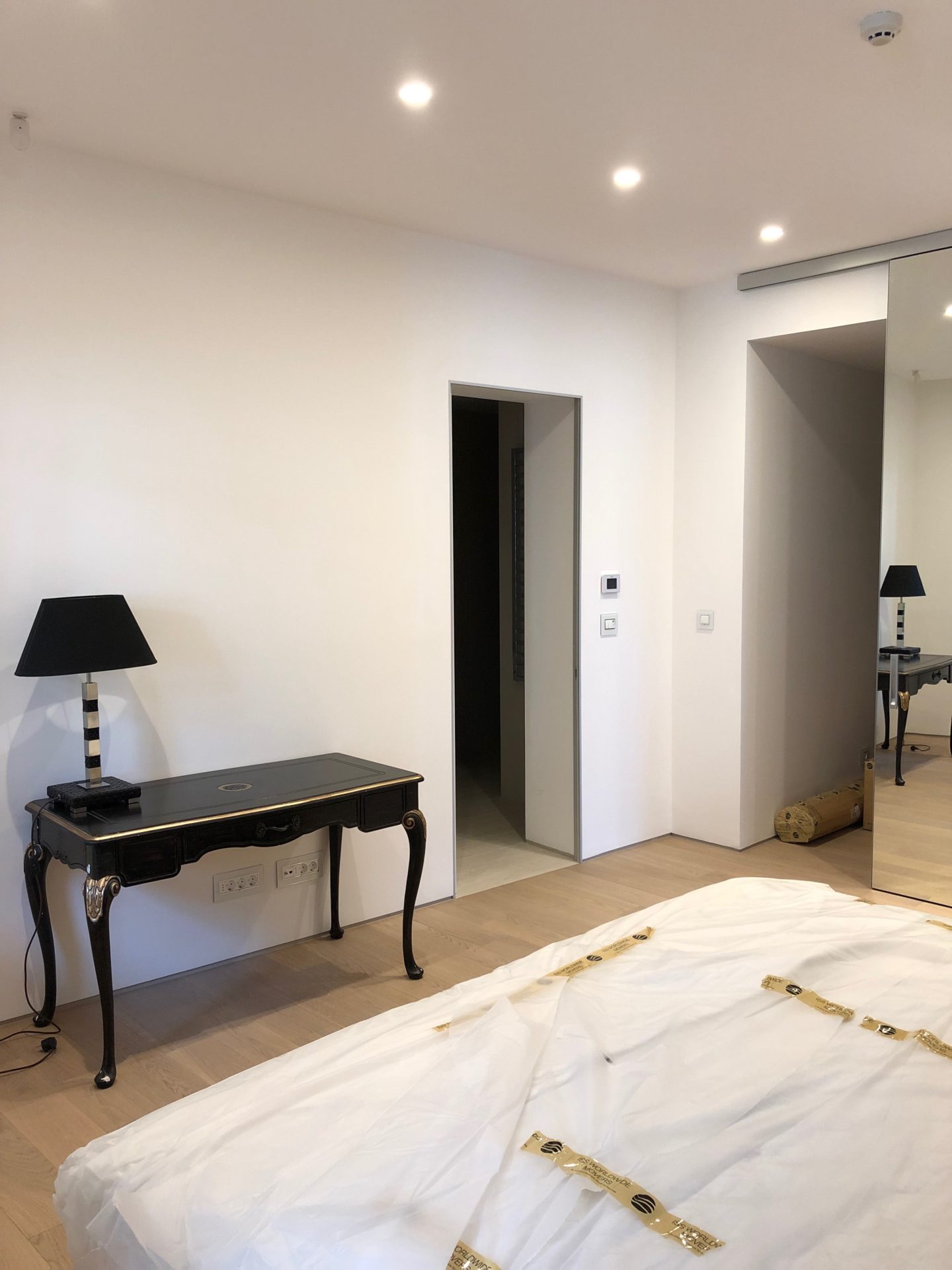 Modernes Schlafzimmer in einer Wohnung in Budva, Montenegro: Vintage-Konsolentisch, schwarze Lampe und Spiegelschrank.