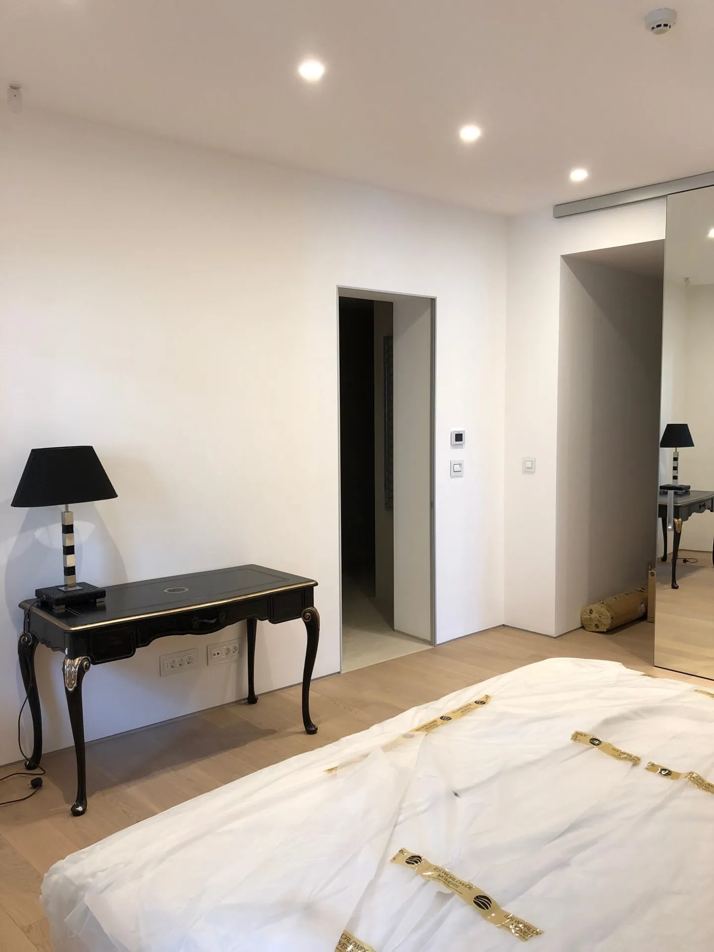 Modernes Schlafzimmer in einer Wohnung in Budva, Montenegro: Vintage-Konsolentisch, schwarze Lampe und Spiegelschrank.