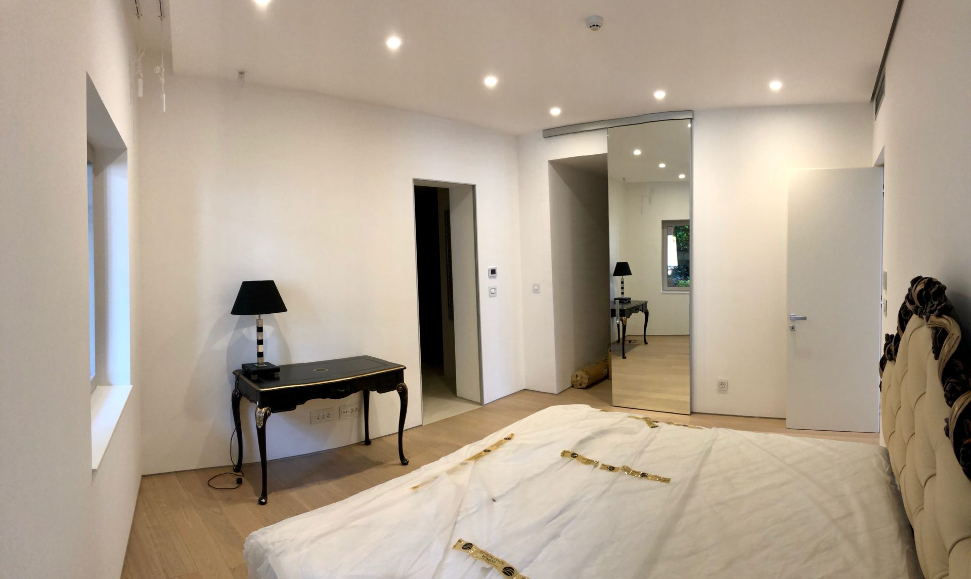 Modernes Schlafzimmer in einer Wohnung in Budva, Montenegro: Doppelbett, Vintage-Tischchen, Spiegel und Spotbeleuchtung.